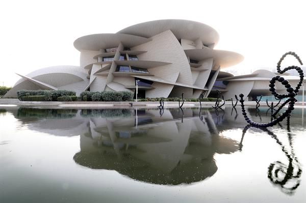 Museo Nacional de Qatar
Localizado en Doha, la capital de Catar, una ciudad moderna completamente renovada para acoger la Copa del Mundo y pensar que es una urbe reciente y tecnológica es algo habitual, pero en sus museos y galerías esconden la esencia de su historia, tradiciones y un vasto legado por explorar.
El  Museo Nacional de Qatar, es el principal museo del país, una joya arquitectónica que encabeza la sorprendente oferta cultural de un país que ha reinventado las tradicionales visitas a museos con muestras interactivas y las últimas innovaciones tecnológicas en las que el futuro marca tendencia.
Obra del arquitecto francés Jean Nouvel, ganador del Premio Pritzker, este monumental edificio evoca la tradición y origen del pueblo catarí, a través de una de sus principales manifestaciones, la rosa del desierto. Una piedra siempre caprichosa y de una belleza sorprendente producto de la cristalización de la arena, el mar y la fuerza del viento.
Sus obras concluyeron en 2019 y fue construído en la zona de los alrededores del palacio original del jeque Abdullah bin Jassim Al Thani, sede del gobierno y residencia particular durante 25 años, y cuyo palacio forma parte de la visita al museo.
Además, la rosa del desierto catarí cuenta con un auditorio de 220 plazas, restaurantes, un centro de investigación y un jardín botánico.
El lago que abraza al museo, con 114 esculturas en su interior, simboliza las dunas y da entrada a una exposición de cerca de 1,5 kilómetros con 11 galerías de caprichosas formas -sin líneas rectas- que permite recorrer la historia y el legado del país, desde sus orígenes prehistóricos y humildes, hasta la época dorada impulsada por el petróleo y el gas.
Pero no es un museo al uso, es probablemente uno de los museos más tecnológicos e interactivos del mundo. Capaz de generar una inmersión total en los visitantes gracias a paredes en las que se proyectan imágenes y sonidos con una definición ultra realista.
Es una experiencia para los sentidos, pero también para profundizar con sus cerca de 8.000 piezas en las comunidades nómadas, el pueblo beduino, los animales del país, objetos arqueológicos y patrimoniales, manuscritos, fotografías, joyas, trajes e incluso un área destinada a la que fue una de sus principales actividades económicas, la pesca de perlas.
En este sentido, cuenta con la alfombra de perlas de Baroda, encargada por el Maharajá de Baroda (India), en 1865 con más de 1,5 millones de perlas y diamantes, rubíes, esmeraldas o zafiros engarzados en oro.
La 'rosa del desierto' es, por méritos propios, la gran experiencia sensorial de la oferta cultural catarí.
