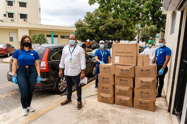 El doctor Felipe Meregildo, administrador del Hospital Robert Reid Cabral, recibe las unidades de gel antibacterial por parte de Vanessa del Villar, gerente de negocios de Laboratorios LAM y personal del laboratorio farmacéutico.
