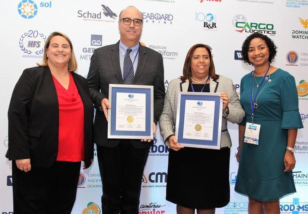 La oficial económica de la embajada de los Estados Unidos, Jenae Jhonson y la presidenta de BASC Dominicana, July de la Cruz, entregan una de las certificaciones a los representantes de la empresa Caribe Trans, Gilda Sánchez y Jean Louis de Boijie.