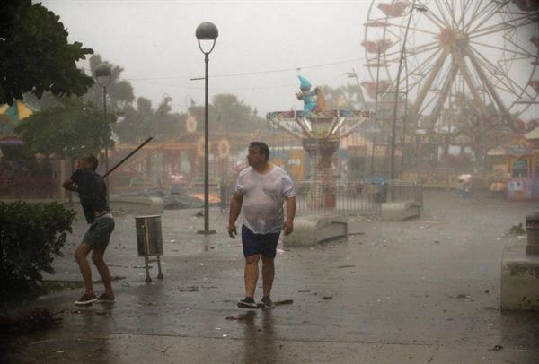 Personas caminan bajo la intensa lluvia durante el paso de la tormenta tropical Fred, hoy en Santo Domingo (República Dominicana). 