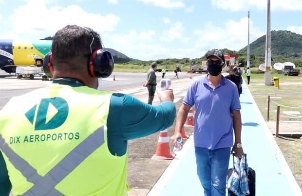 Fotografía cedida este lunes por la ONG Sistema Golfinho-Administración Fernando de Noronha en la que registró a un trabajador aeroportuario al realizar controles de temperatura a los pasajeros que llegan al archipiélago de Fernando de Noronha, Brasil.