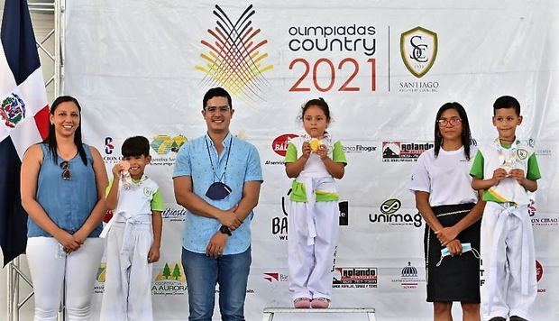  El arquitecto Willy Rodríguez, presidente del Santiago Country Club, quien aparece al centro y las señoras madres de atletas, Cinthia Ortiz y Reysi Simón, en los extremos, entregan las primeras medallas que se otorgan en Las Olimpiadas Country, a los ganadores de la tercera categoría, oro, Daniela Estévez, en el centro; plata, Jordan Santos, en la derecha y bronce, Dylan Peña, en la izquierda.