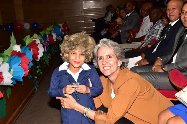 Virginia (Ginny) Heinsen posa a la cámara junto a niña asistente a su reconocimiento.