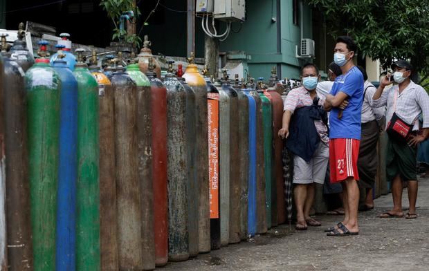 La gente de Myanmar espera cerca de tanques de oxígeno alineados para rellenar fuera de una fábrica de oxígeno en Yangon, Birmania, pues se enfrenta a una escasez de oxígeno para tratar a pacientes críticos debido al creciente número de casos de COVID-19 en todo el país.