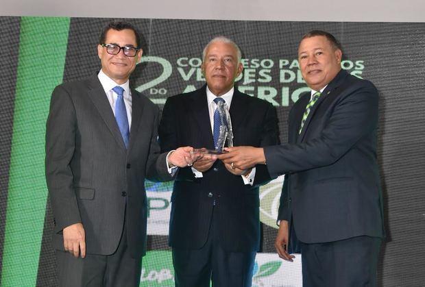 Eddy Olivares, Andrés Bautista, y Antolín Polanco sostienen estatuilla en honor a Orlando Jorge.