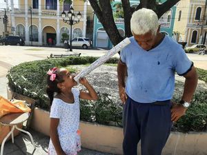 Una niña de seis años lee a un viandante sus poemas haikus, en calles de Puerto Plata.