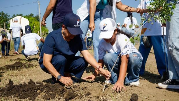 La doctora Carmen Alicia Quijano, presidente del Voluntariado Banreservas, siembra árbol junto a su nieta.