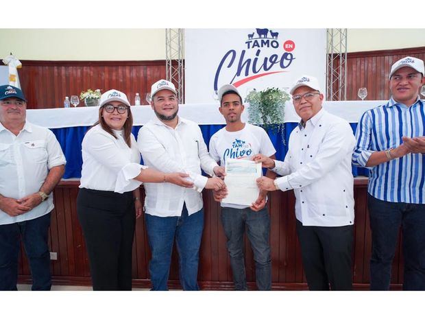 Hecmilio Galván y Juan Rosario entregan un cheque a uno de los beneficiarios del proyecto de ovicaprinos.