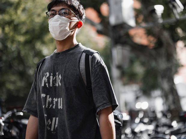 Un hombre camina por la calle en Shanghai, China, protegido con una mascarilla.