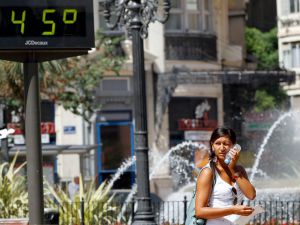 Una joven trata de refrescarse junto a una fuente y un termómetro que marca 45 grados.