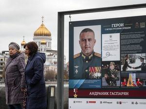 Dos mujeres rusas pasan junto a fotos de militares que lucharon en Ucrania.
