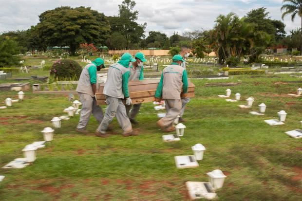 Trabajadores cargan el féretro para enterrar a una víctima de covid-19, en el cementerio Campo da Esperança, en la ciudad de Brasilia, Brasil.
