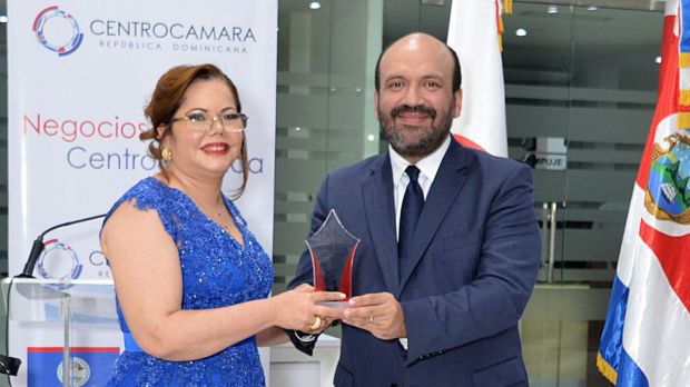 Ramón Pérez Fermín, viceministro de Economía y MiPyme entrega un reconocimiento a Kathy Grullon.