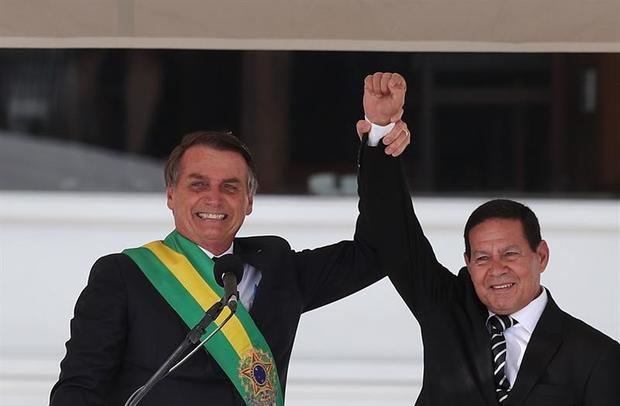 El nuevo presidente de Brasil, Jair Bolsonaro (i), saluda junto al vicepresidente, Hamilton Mourão, durante la ceremonia de investidura celebrada hoy en el Palacio de Planalto, Brasilia (Brasil), en la que Bolsonaro recibió la banda presidencial de parte de su predecesor