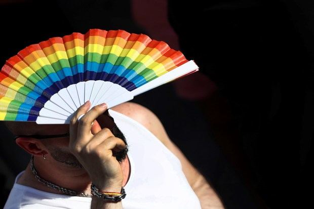 Un hombre se protege del sol momentos previos a la lectura del pregón del Orgullo 2019, en la plaza de Pedro Zerolo, en Madrid. 