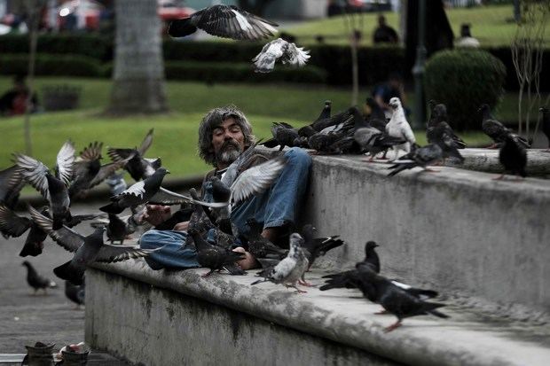 Fotografía del 30 de septiembre de 2019 que muestra a un hombre que canta afuera de un local comercial cerrado en el centro de San José, Costa Rica.