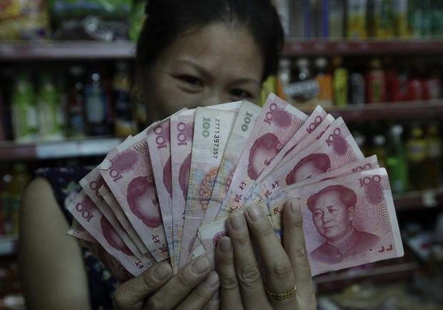 Una vendedora muestra billetes de yuan en Pekín (China) hoy, 11 de agosto de 2015. El Banco Popular de China (central) devaluó hoy un 1,86 % la cotización de referencia del yuan con respecto al dólar y afirmó que en los últimos meses el tipo de cambio de la moneda china 'se había desviado del mercado'. El regulador chino, que cada día fija un precio medio del tipo de cambio del yuan con el dólar y permite que fluctúe hasta un máximo de un 2 %, anunció en un comunicado esta corrección de la valoración de la moneda china y la definió como una 'mejora'.