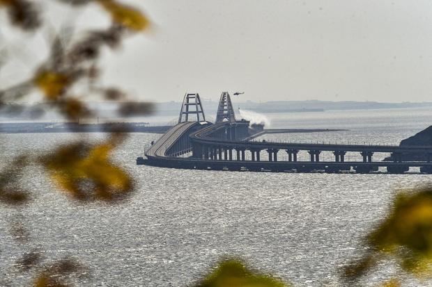 Un helicóptero de bomberos vierte agua sobre una parte derrumbada del puente del estrecho de Kerch, en Crimea, el 8 de octubre de 2022, tras un ataque atribuido a fuerzas ucranianas.