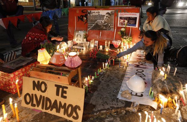 Un grupo de personas enciende velas en el lugar donde el joven estudiante Dilan Cruz recibió un disparo por parte de un miembro de la policía en el marco de una movilización parte del paro nacional, durante la tradicional noche de las velitas que marca en muchas ciudades del país el inicio de la Navidad, este sábado, en la Plaza de Bolívar, en Bogotá (Colombia).