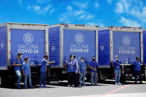Vista de trabajadores de la salud junto a camiones refrigerantes que transportarán un lote de vacunas, en una fotografía de archivo.