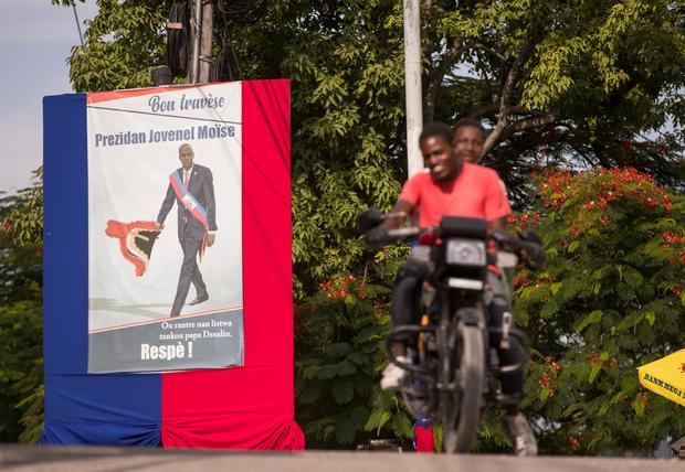 Personas pasan hoy junto a un altar en homenaje al asesinado expresidente Jovenel Moise, en Puerto Príncipe, Haití.