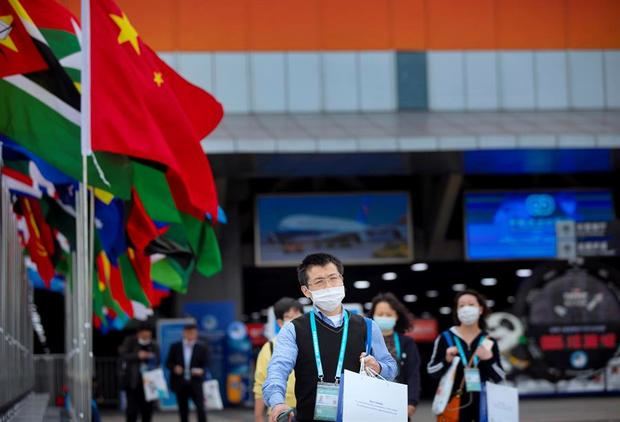 Los visitantes, protegidos con mascarillas, caminan frente a la 3ª Exposición Internacional de Importación de China en Shanghai, China.