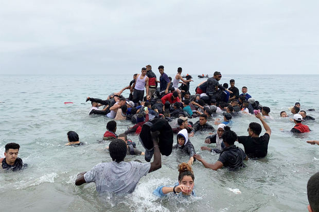 Un grupo de personas se hacen con una embarcación de las autoridades marroquíes en la playa de la localidad de Fnideq (Castillejos) para cruzar los espigones de Ceuta.