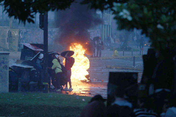 Manifestantes se protegen del fuego con escudos y barricadas durante los enfrentamientos con miembros de la policía a los alrededores de la Casa de la Cultura, en Quito, Ecuador.