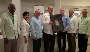 El presidente de FENCOOP, Francisco Estepan Herrera, mientras recibe del presidente del Consejo Directivo de AIRAC, Alfredo Darío Dorrejo, la placa de reconocimiento a su desempeño. Les acompañan Julio Enrique Caminero, María del Carmen Rodríguez, Luis López y Juan Aquino Bueno.