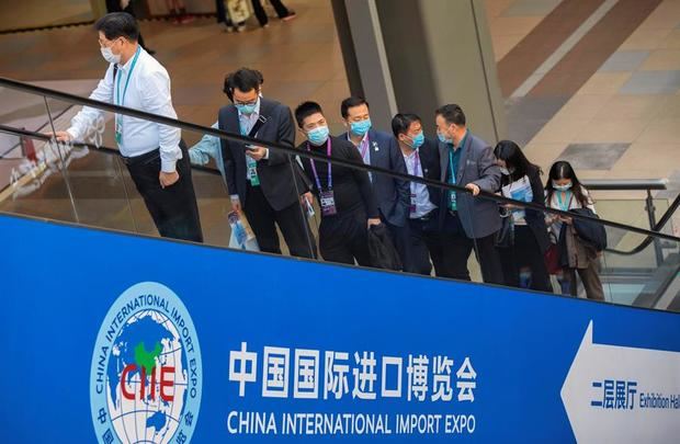 Numerosos visitantes montan en una escalera mecánica en la 3ª Exposición Internacional de Importación de China en Shanghai, China.