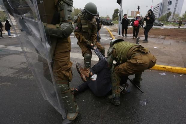 Integrantes de la Policía de Chile (Carabineros) arrestan a un hombre durante una protesta en contra del Gobierno del presidente chileno Sebastián Piñera hoy, en la plaza Italia en Santiago, Chile.