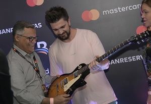 Juanes entrega una guitarra autografiada a uno de los tres ganadores del concurso auspiciado por Banreservas y Mastercard.