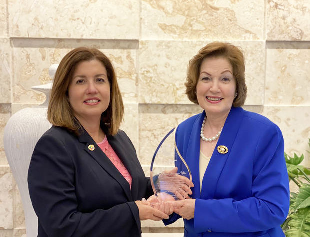 La presidenta de Adesinc, Lucile Houellemont, entrega el reconocimiento a Clara Elena Jimenes Alfau.