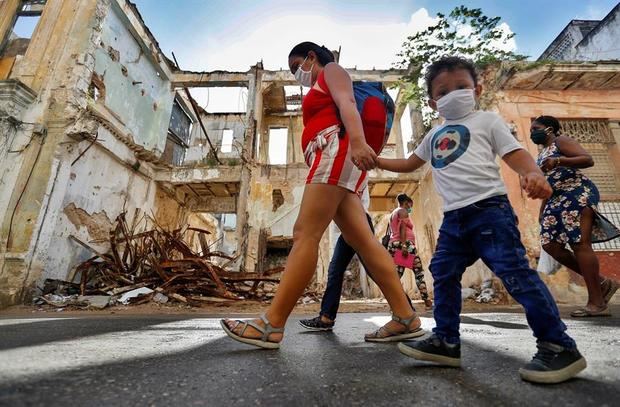 Varias personas caminan por la calle usando mascarillas para protegerse del coronavirus, este sábado, en La Habana, Cuba.