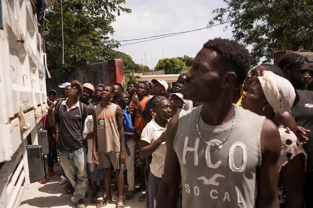 Personas esperan para recibir comida que repartiría el Programa Mundial de Alimentos, este viernes en Camp Perrin, Haití.