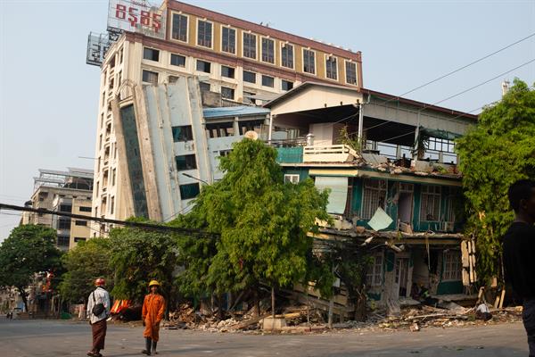 Un par de rescatistas fue registrado este sábado, 29 de marzo, al caminar frente a un edificio afectado por el terremoto de magnitud 7.7 que azotó el viernes a Birmania, en la ciudad de Mandalay. 