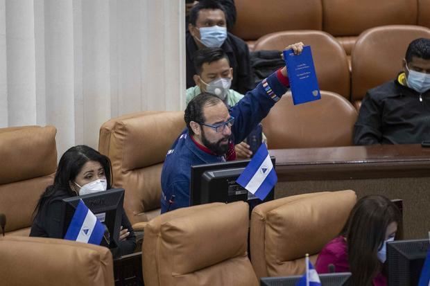 El diputado del FSLN, Carlos Emilio López levanta un libro de la constitución de Nicaragua durante una sesión ordinaria en la asamblea nacional (AN), este 16 de noviembre del 2021en Managua, Nicaragua.