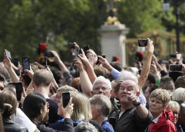 Personas llegadas al Palacio de Buckingham en Londres hacen fotografías al rey Carlos III y Camila, la reina consorte, este 9 de septiembre.