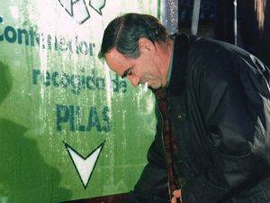 Un ciudadano deposita unas pilas en un contenedor en una céntrica calle de Madrid. 