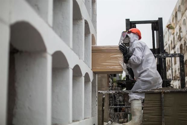 Un trabajador empuja un féretro hacia una tumba el pasado 25 de mayo del 2020 durante su funeral en el cementerio El Ángel en Lima, Perú.