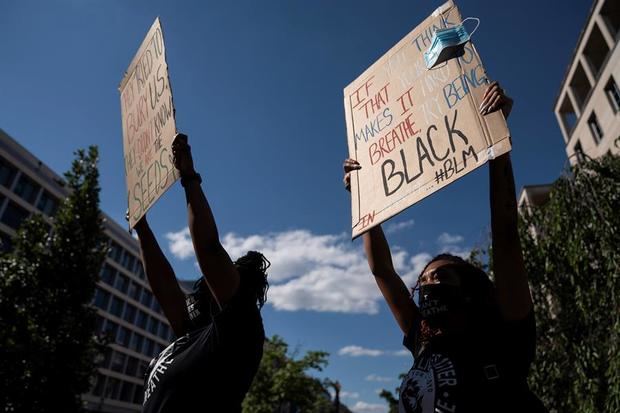 La gente levanta carteles en protesta cerca de la Casa Blanca, donde ha habido una semana de protestas por la muerte de George Floyd, quien murió bajo custodia policial, en Washington, DC.