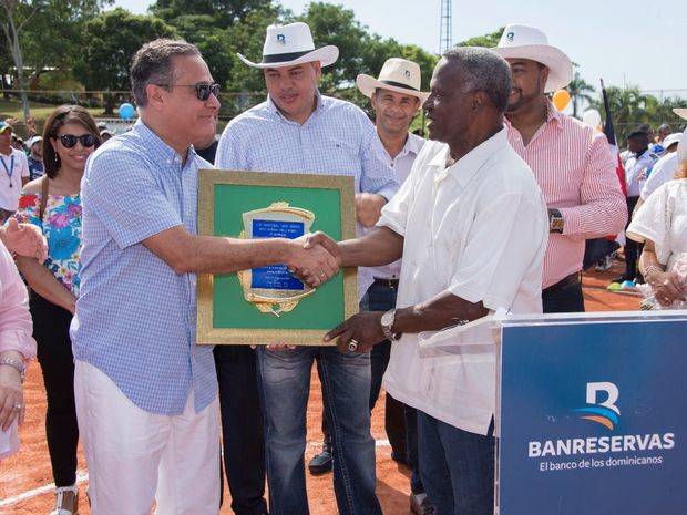 El subadministrador de Empresas Subsidiarias de Banreservas, Rienzi Pared Pérez, entrega una placa de reconocimiento al expelotero de Grandes Ligas Manuel Mota, durante la inauguración de los Juegos Deportivos Familia Banreservas.
