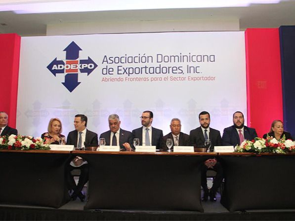 Mensa central: Luis Espinola Moya, secretario del consejo de directores de Adoexpo;  Alma Fernández, directora de Proindustria; Luis Henry Molina, director ejecutivo del CEI-RD; Miguel Vargas, canciller; Álvaro Sousa Sevilla, presidente de Adoexpo; Isidoro Santana, ministro de Economía, Planificación y Desarrollo; Rafael Paz, director de ProCompetitividad; Víctor Gómez Casanovas, director de la Autoridad Portuaria Dominicana; Luisa Fernández, directora del Consejo Nacional de Zonas Francas de exportación, y Sadala Khoury, pasado presidente de Adoexpo.