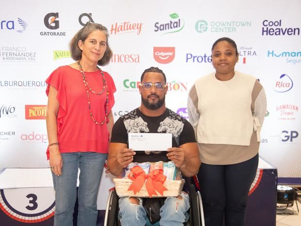 Frankely Paredes, ganador de la categoría en silla de ruedas masculino, recibe su premio de manos de Karine Noetinger y Maleidy Ramírez