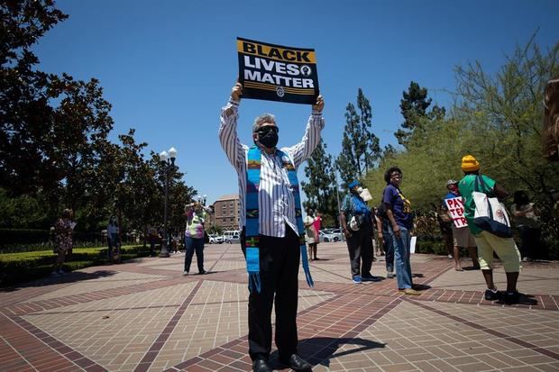 Un pastor sostiene un cartel durante una protesta de 'Black Lives Matter' (Las vidas negras importan), en las afueras de la Universidad del Sur de California en Los Ángeles, EE.UU.