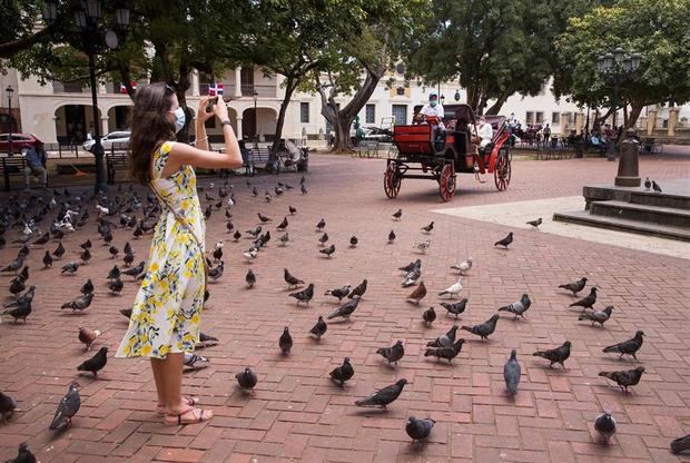 Una turista toma fotografías en el parque Colón mientras que coches impulsados con energía eléctrica circulan por la zona colonial hoy en Santo Domingo, República Dominicana.