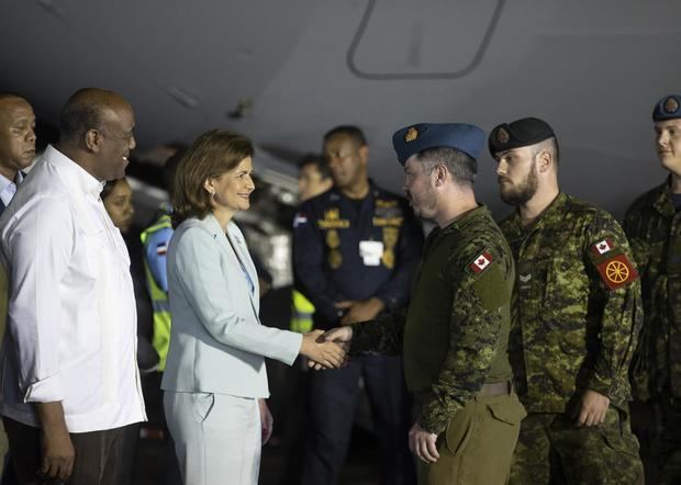 La vicepresidenta dominicana Raquel Peña (2i) y el ministro de Energía y Minas, Antonio Almonte, saludan a tripulantes del avión militar procedente de Canadá, antes del inicio de la descarga de la ayuda para el rescate de los dos trabajadores 