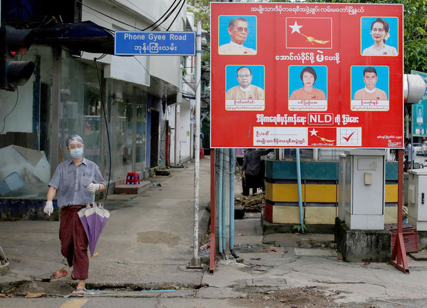 Un hombre con mascarilla se acerca a un letrero de campaña electoral del partido de la Liga Nacional para la Democracia (LND), dirigido por la Consejera del Estado de Myanmar, Aung San Suu Kyi, en Yangon, Birmania, elecciones que ganó el 8 de noviembre de 2020.