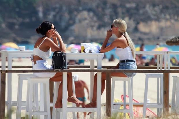 Dos turistas en una terraza disfrutan de un soleado día en la playa de Los Lances, en Tarifa (Cádiz).