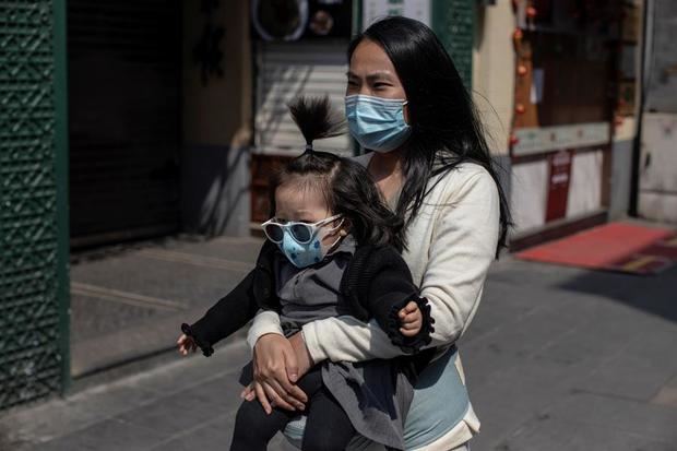 Una mujer y un bebé, con mascarillas, pasean por la calle comercial Qianmen de Pekín (China) este viernes, en medio de la pandemia por coronavirus.